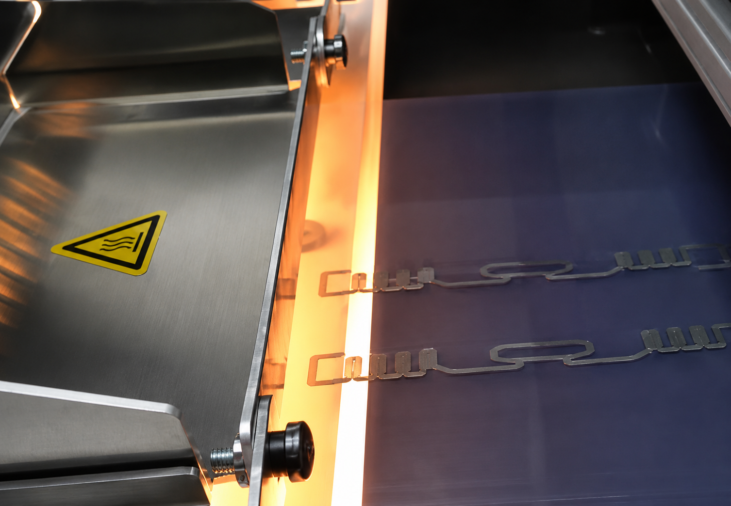 Printed Electronics Prozess: Es wird Silbertinte auf durchsichtiger Folie gedruckt und es wird der Produktionsprozess gezeigt. Die Folie kommt gerade aus der thermischen Behandlung. Es sind keinerlei wärmebasierte negative Auswirkungen erkennbar.